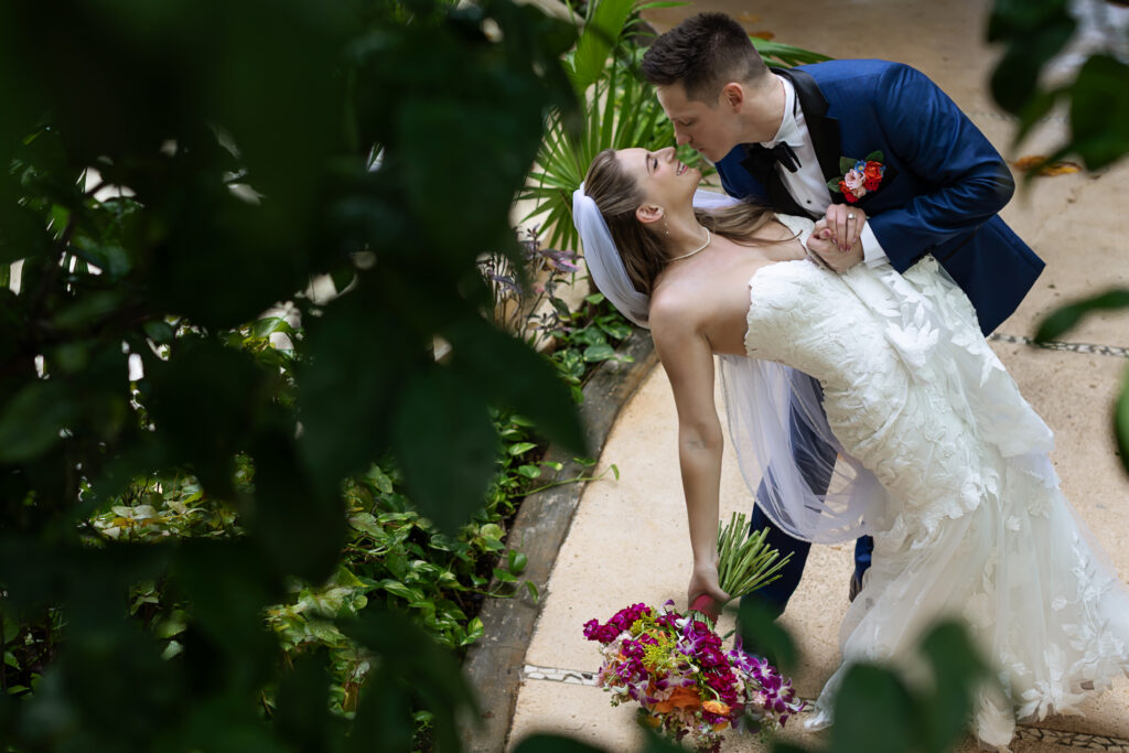 Casey and Gage sharing a dip kiss in the garden at Live Aqua Cancun on their destination wedding day